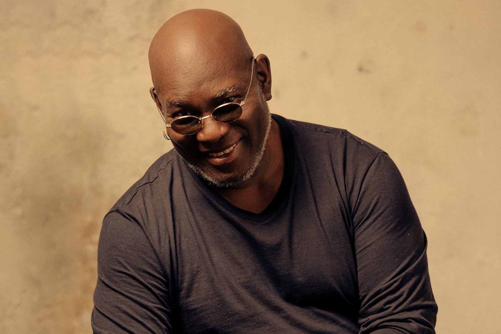 homem negro de óculos escuros e careca sentado