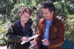 temple-grandin-cena-filme-jovem-mexendo-em-modelo-de-madeira-ao-lado-de-homem-em-parque-historia-real-neurodiversidade