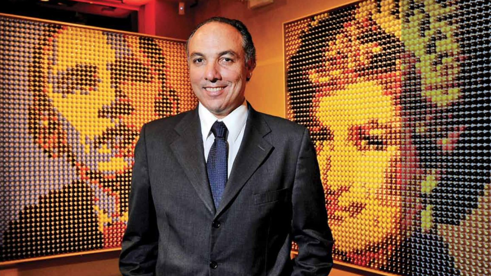 Ricardo Bellino diante de obras da coleção ArtCaps feitas com cápsulas de café recicladas.