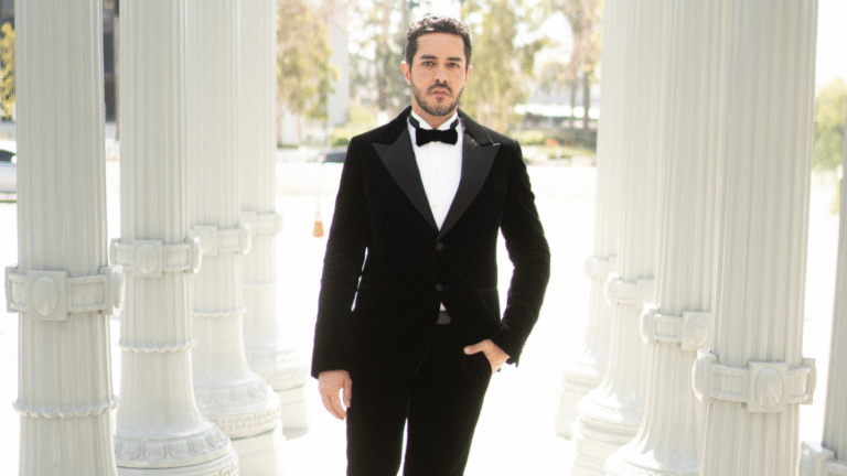João Brasio em traje formal (black tie) em ambiente com colunas clássicas, associado a eventos internacionais do entretenimento