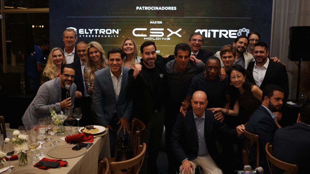 Grupo de empresários, autoridades e participantes reunidos durante jantar do Protagonistas do Brasil, em ambiente corporativo, com destaque para os patrocinadores exibidos ao fundo e interação entre lideranças.