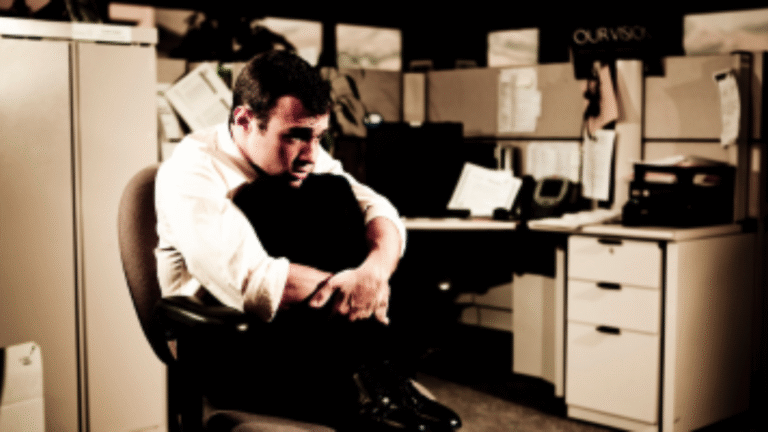 Homem sentado em ambiente corporativo, com postura retraída e expressão de preocupação, representando insegurança diante de mudanças no trabalho