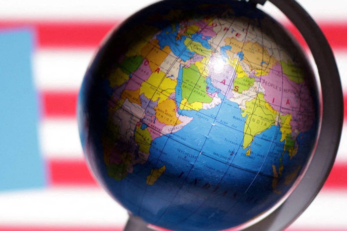 Globo terrestre em primeiro plano mostra continentes coloridos. Ao fundo, desfocados, estão a bandeira dos Estados Unidos e o logo azul da FDA.
