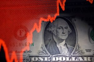 Gráfico de linha vermelha em alta sobreposto parcialmente à imagem da nota de um dólar americano com o retrato de George Washington.