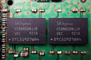 Dois chips pretos SK hynix com inscrições idênticas estão montados lado a lado em uma placa de circuito verde com componentes eletrônicos ao redor.