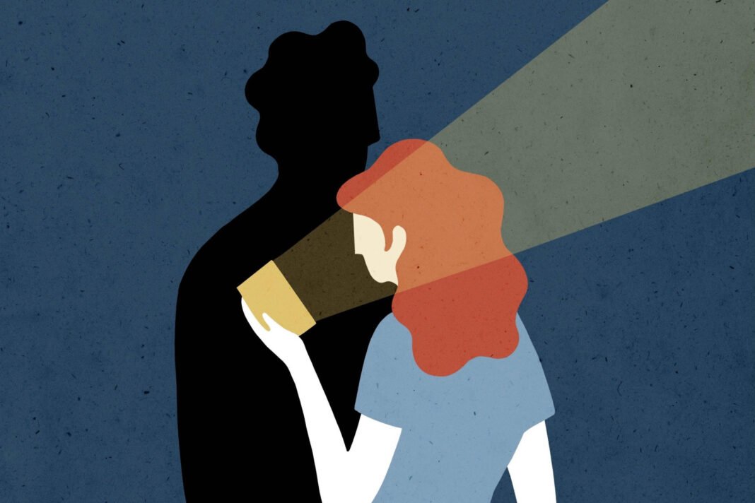 A imagem apresenta uma ilustração estilizada de uma mulher com cabelo ruivo e ondulado, segurando um objeto que emite luz, direcionada para uma sombra de uma figura masculina ao fundo. O fundo é de uma cor azul escura, e a luz projetada cria um contraste com a silhueta da figura masculina, que é completamente preta. A mulher está vestida com uma camiseta azul clara e a luz que emite é de uma cor amarelada.