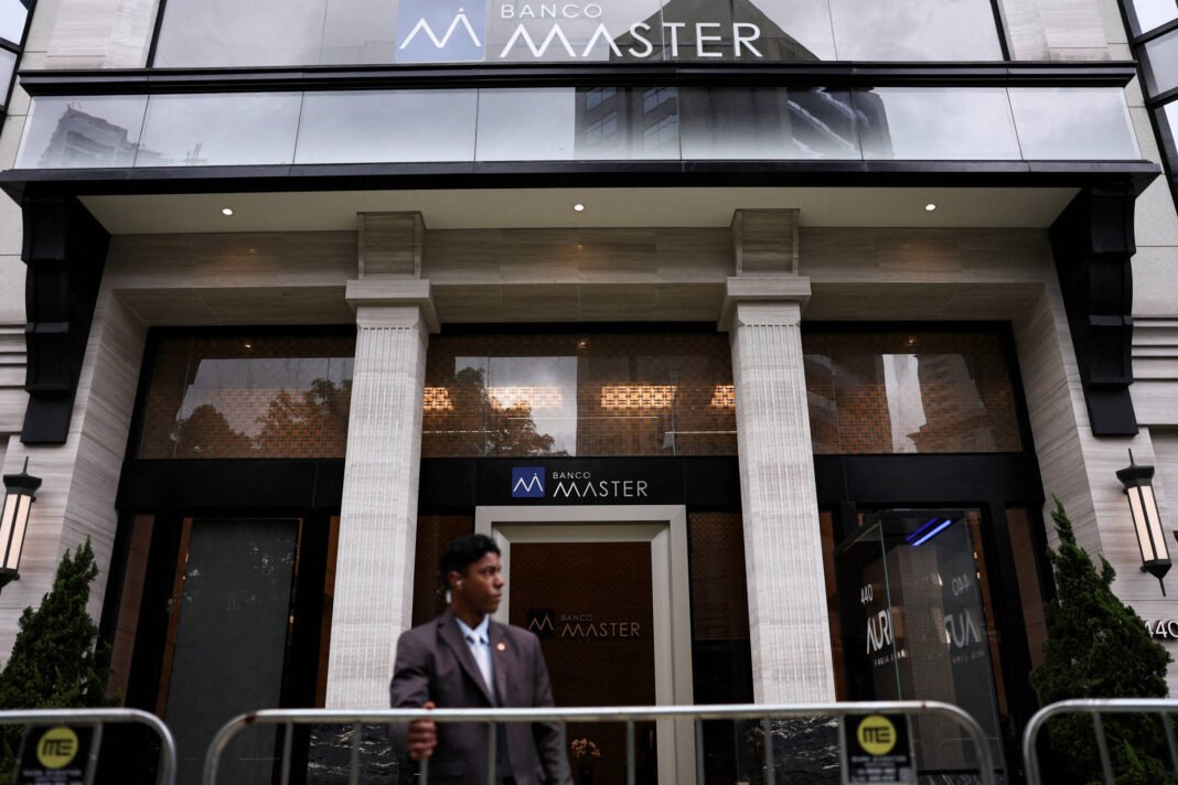 Fachada do Banco Master com colunas brancas e vidro refletivo. Homem de terno escuro está em frente, atrás de uma grade de segurança.