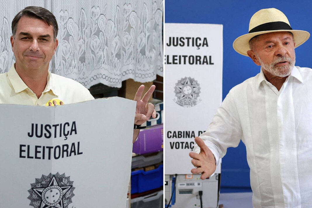 À esquerda, homem de camisa clara faz sinal de paz com as duas mãos atrás de cabine de votação com inscrição 