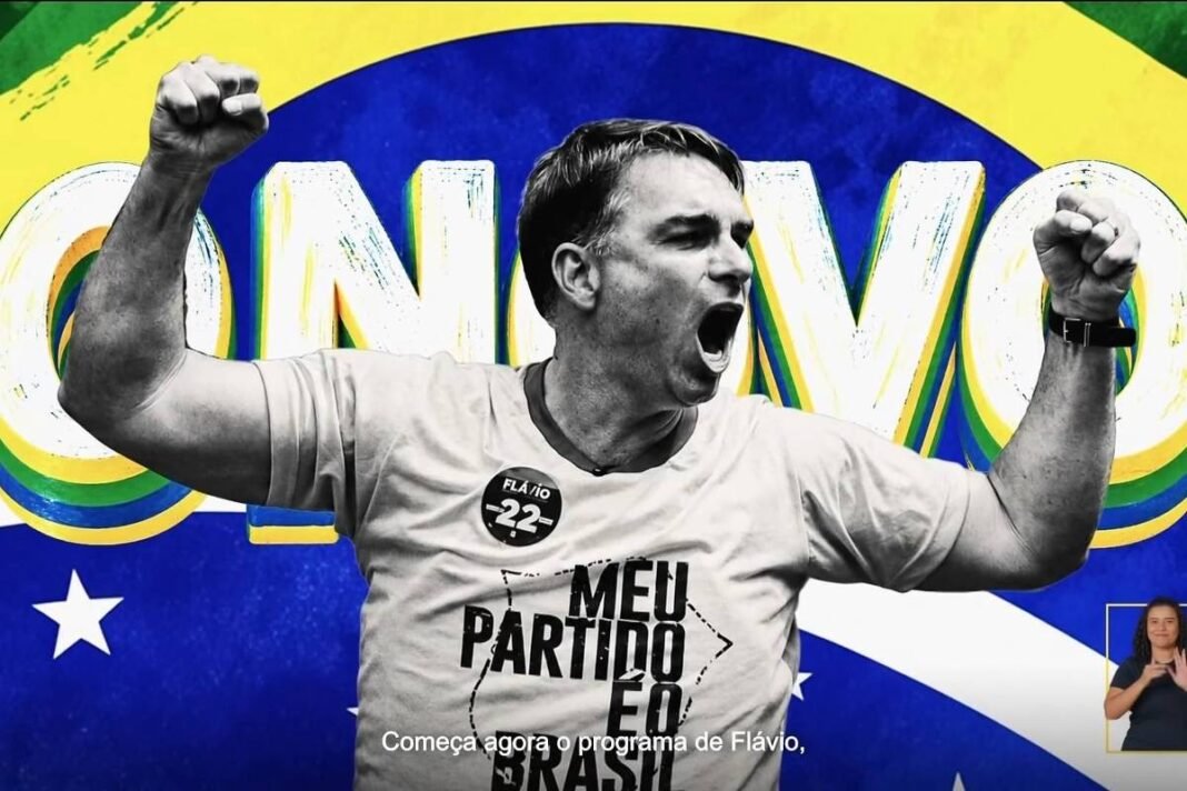 Homem de camiseta branca com texto e botão comemorativo levanta os punhos e grita em frente a bandeira do Brasil estilizada com a palavra 